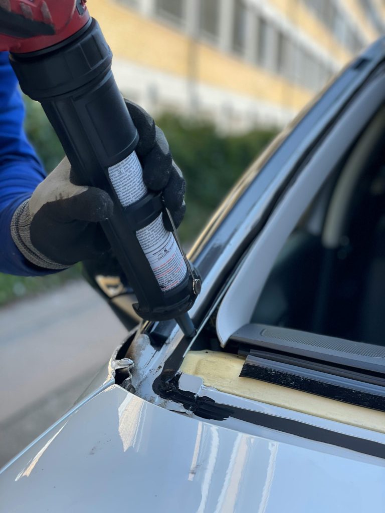 Gros plan sur un technicien réparant un pare-brise de voiture dans un atelier de Copenhague.